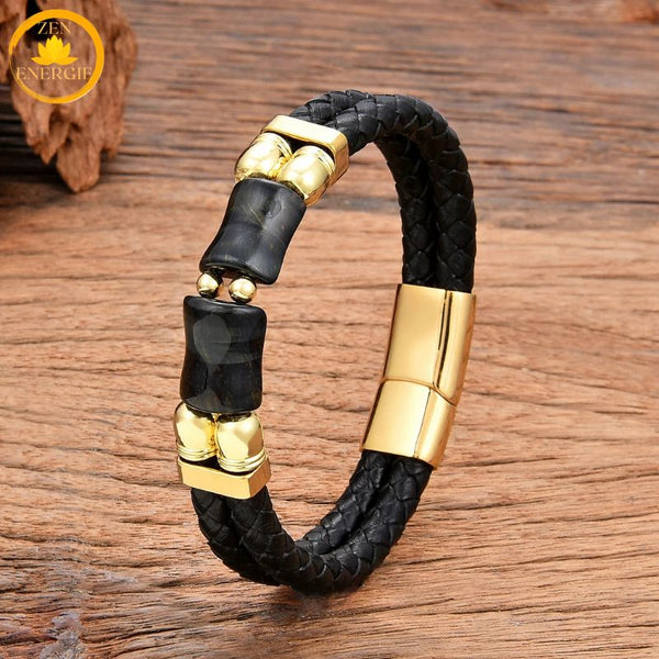 alt="Bracelet homme en cuir tressé noir avec pierre œil de faucon bleu-gris et fermoir doré"
