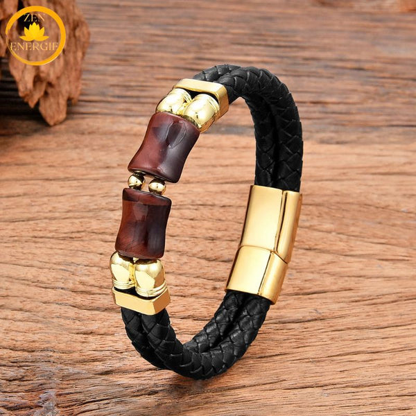 alt="Bracelet homme en cuir tressé noir avec pierre œil de taureau rouge et fermoir doré"

