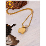 alt="Collier doré avec pendentif hexagonal poli, bijou élégant posé sur tissu clair"
